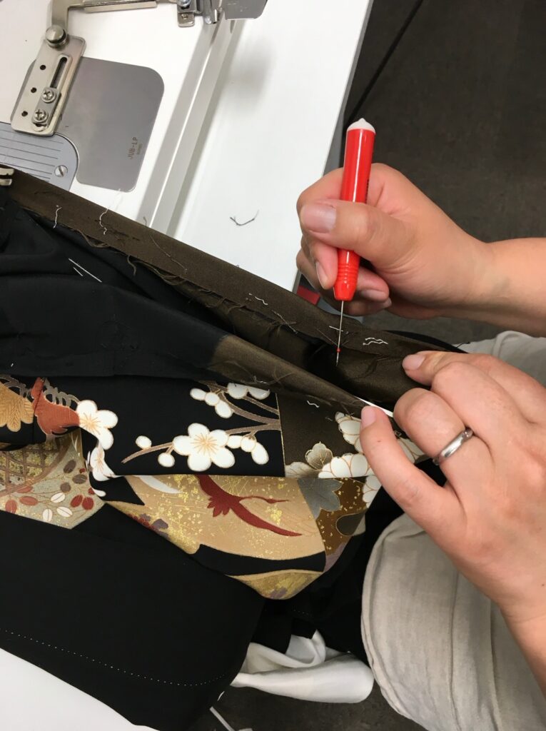 黒留袖の縫い目を一針ずつほどく職人の手元